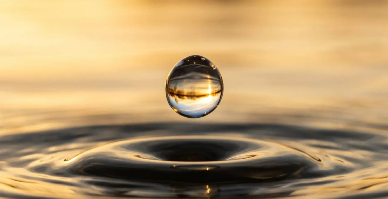 Makroaufnahme eines Wassertropfens, der im Moment des Einfrierens goldenes Licht einfängt und einen visuellen Bruch erzeugt